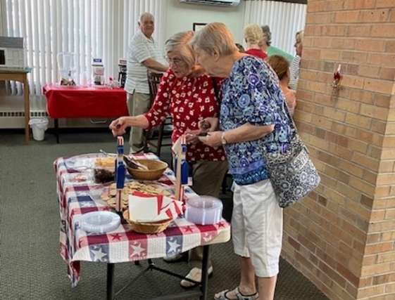 Two friends look at items on table during a social event 