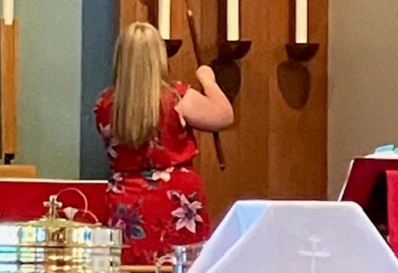 A woman lights a candle at church service 
